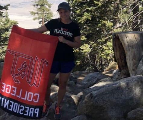 Brianna McGowan stops on a hike to pose with a W&J flag.